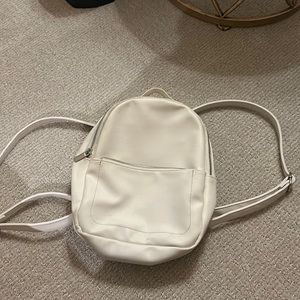 White mini backpack. Blue stains in the inside of the backpack.